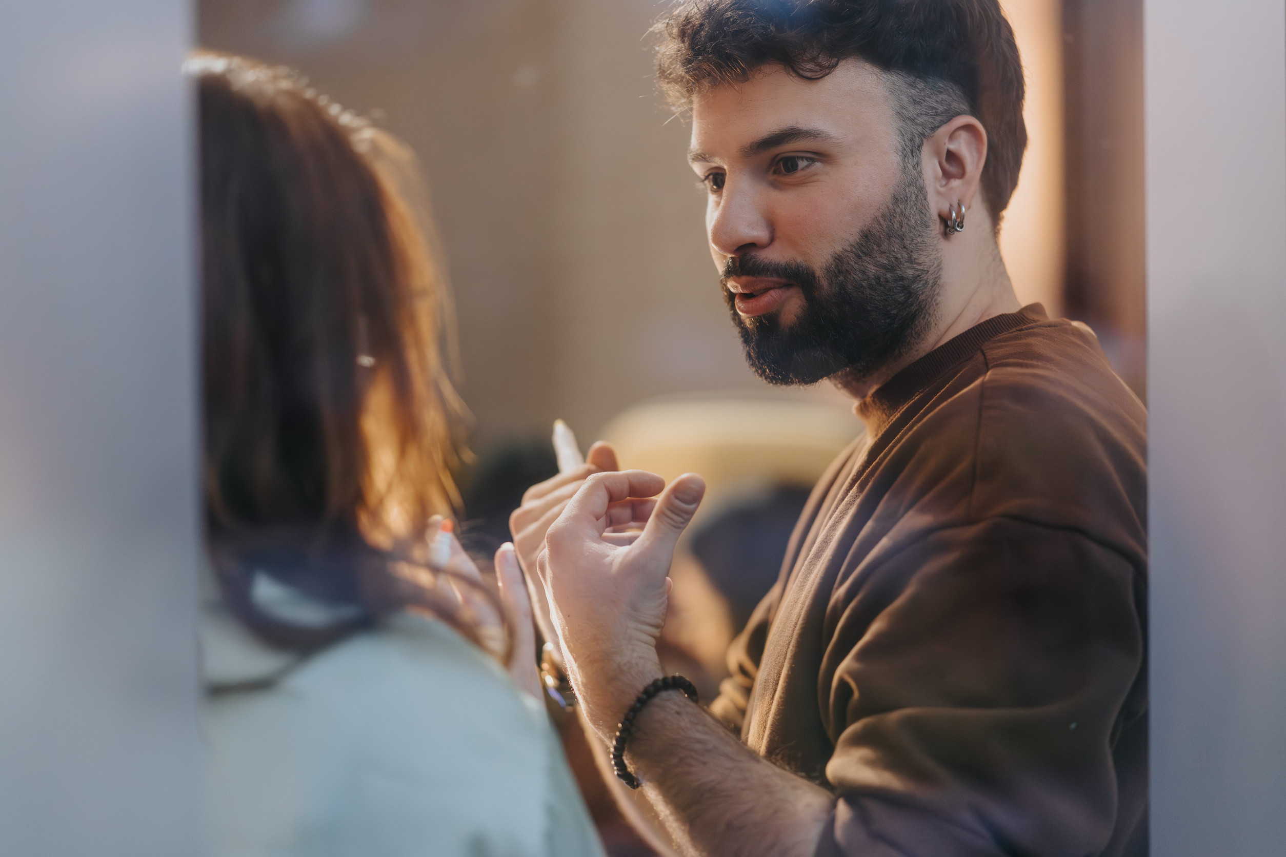 Bearded man talking to unseen person, warm toned casual conversation.